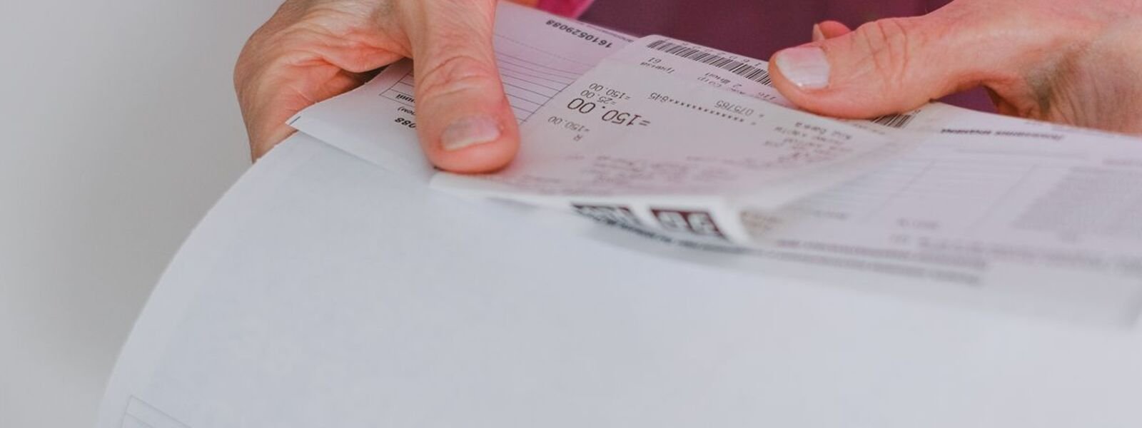 Close-up of hands unfolding a printed itemised hospital statement.